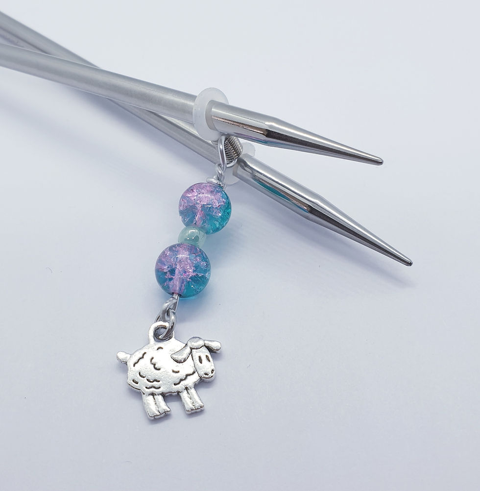 Knitting needles with rubber band wrapped round ends and beads and charm attached to rubber band