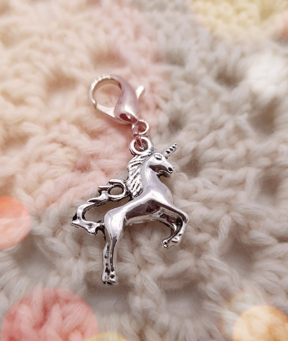 Thumbnail: unicorn shaped silver coloured metal charm with clasp on crochet square background