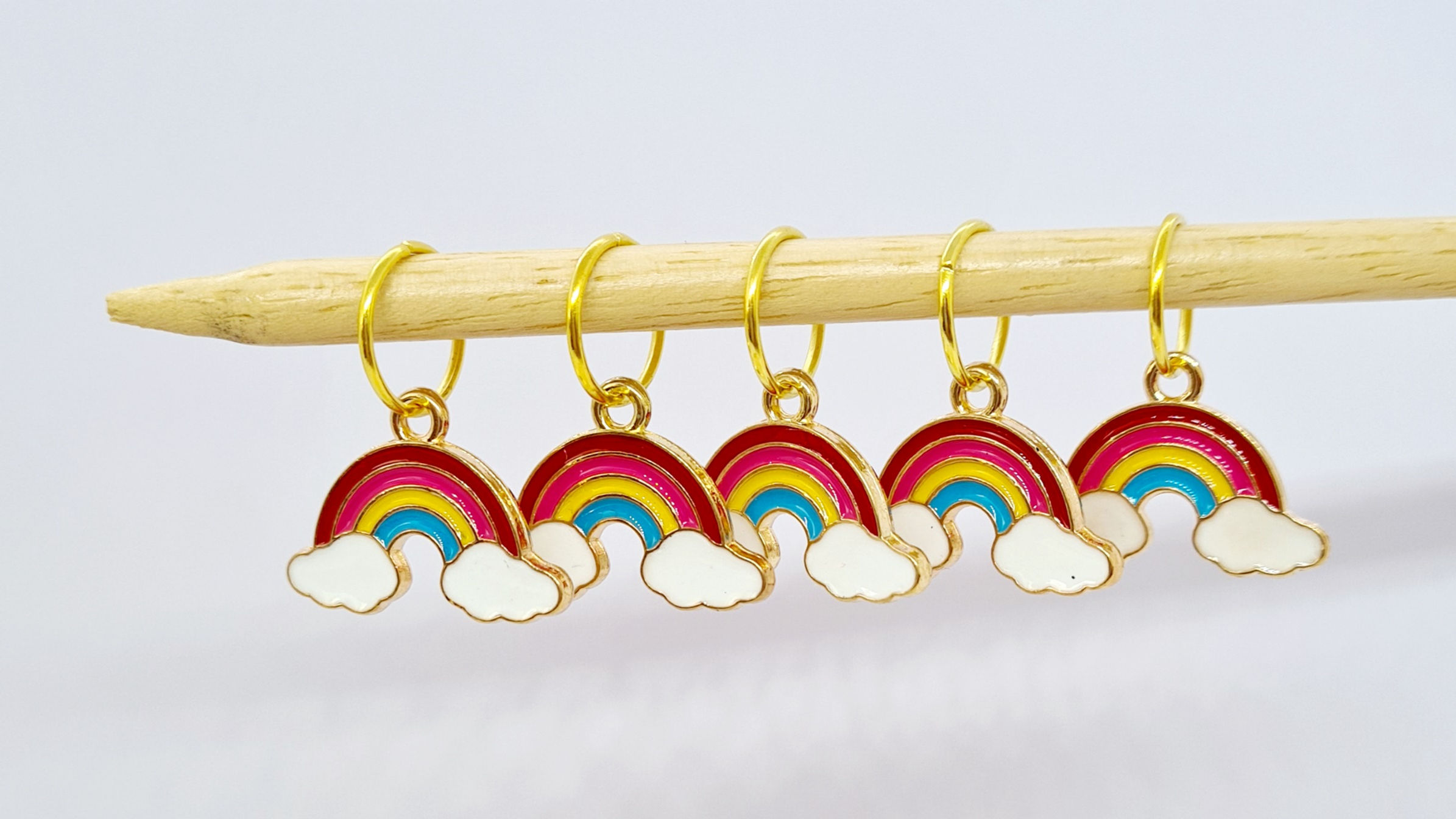 5 enamel rainbow with a cloud at each end charms on a gold coloured metal back with rings on a knitting needle