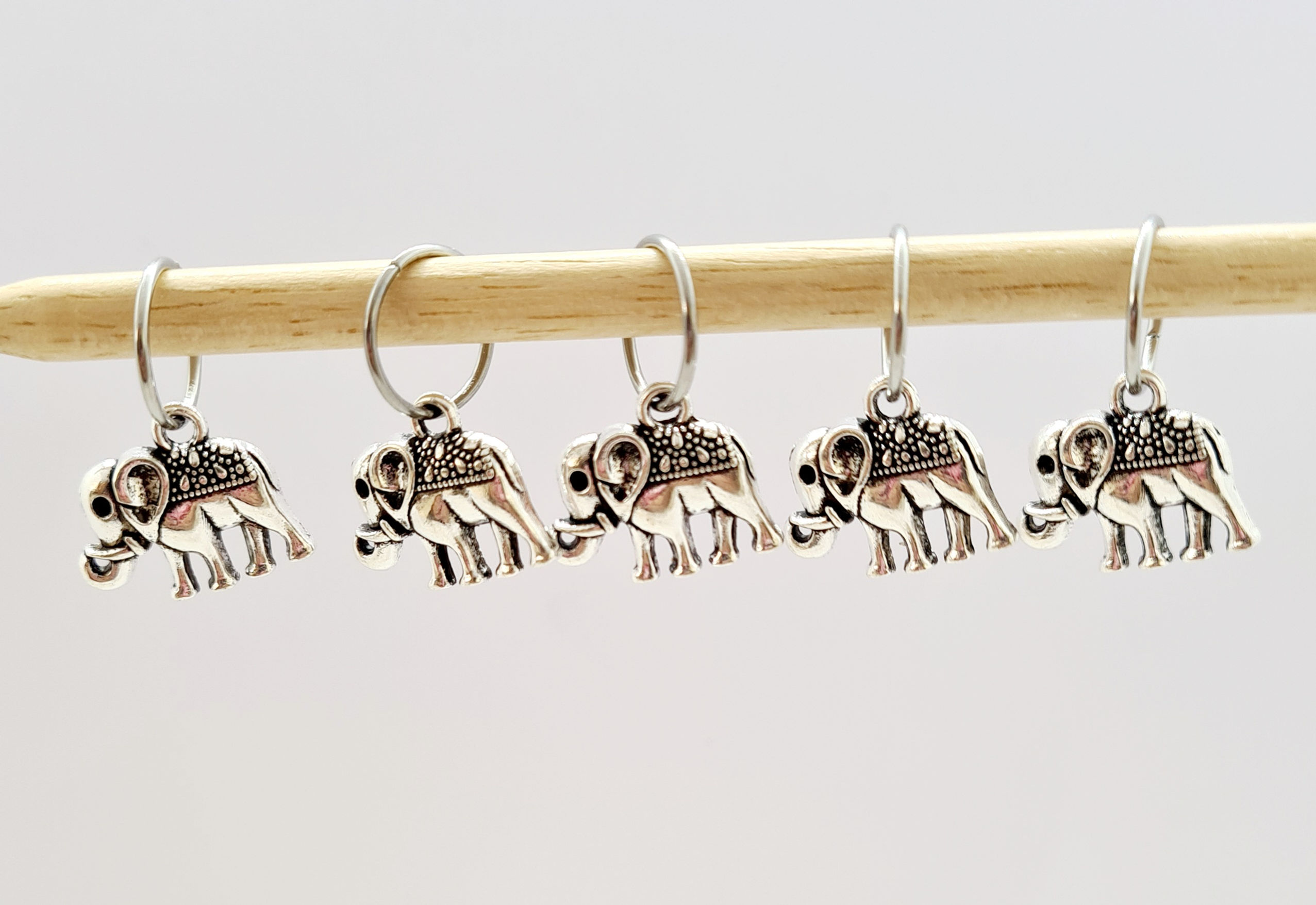 5 silver coloured metal charms of elephants with rings on knitting needles