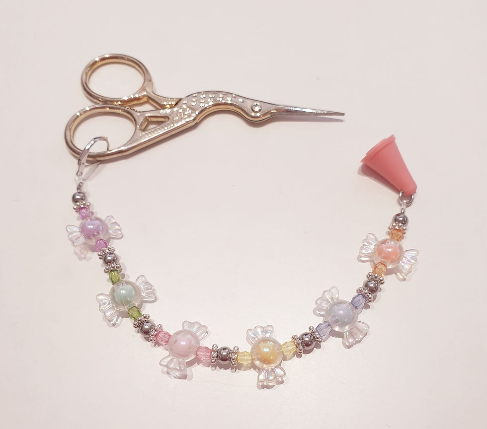 scissors with beaded rope attached to handle and rubber cap over points