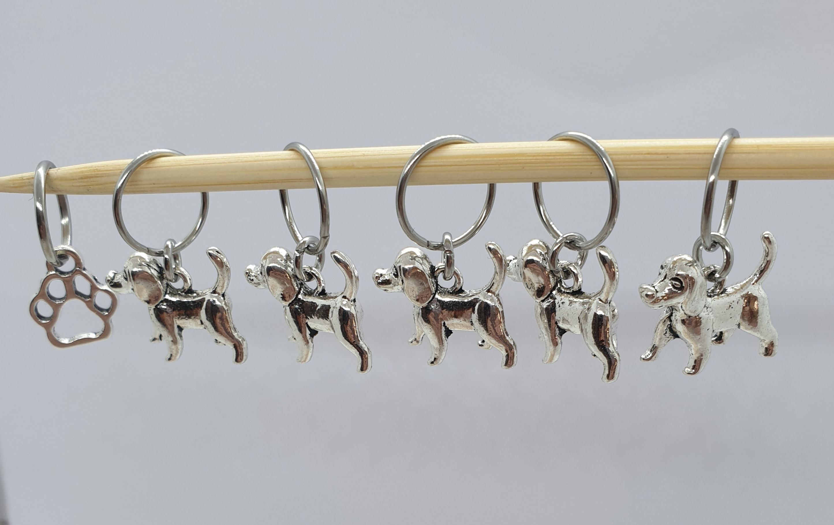 dog shaped silver coloured charms with rings on a wood knitting needle