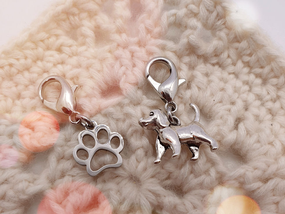 Thumbnail: dog shape and paw print shape stitch markers with clasps on a granny square