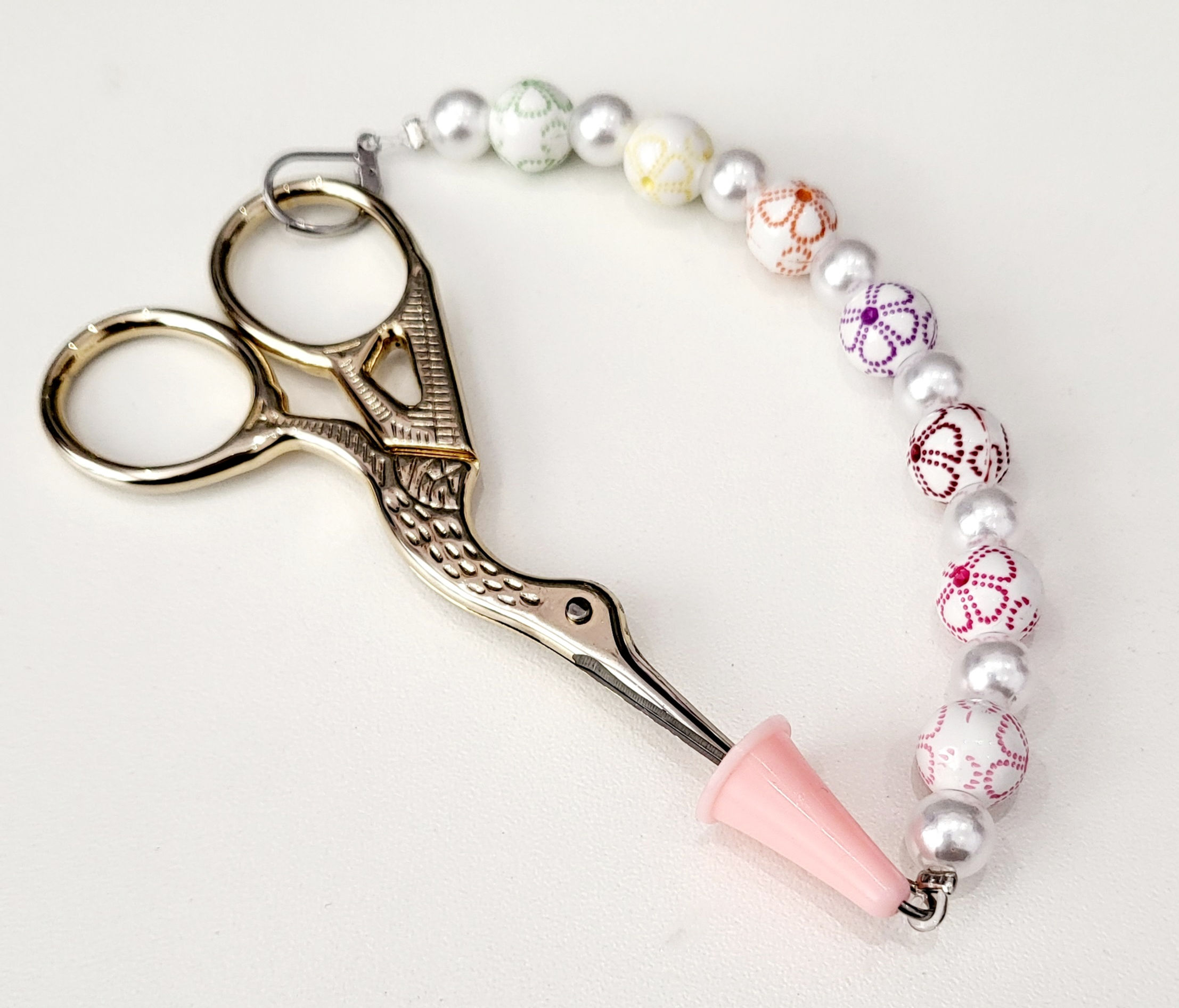 Scissors with beaded rope attached on handle with removable clasp at one end and rubber cap at the other