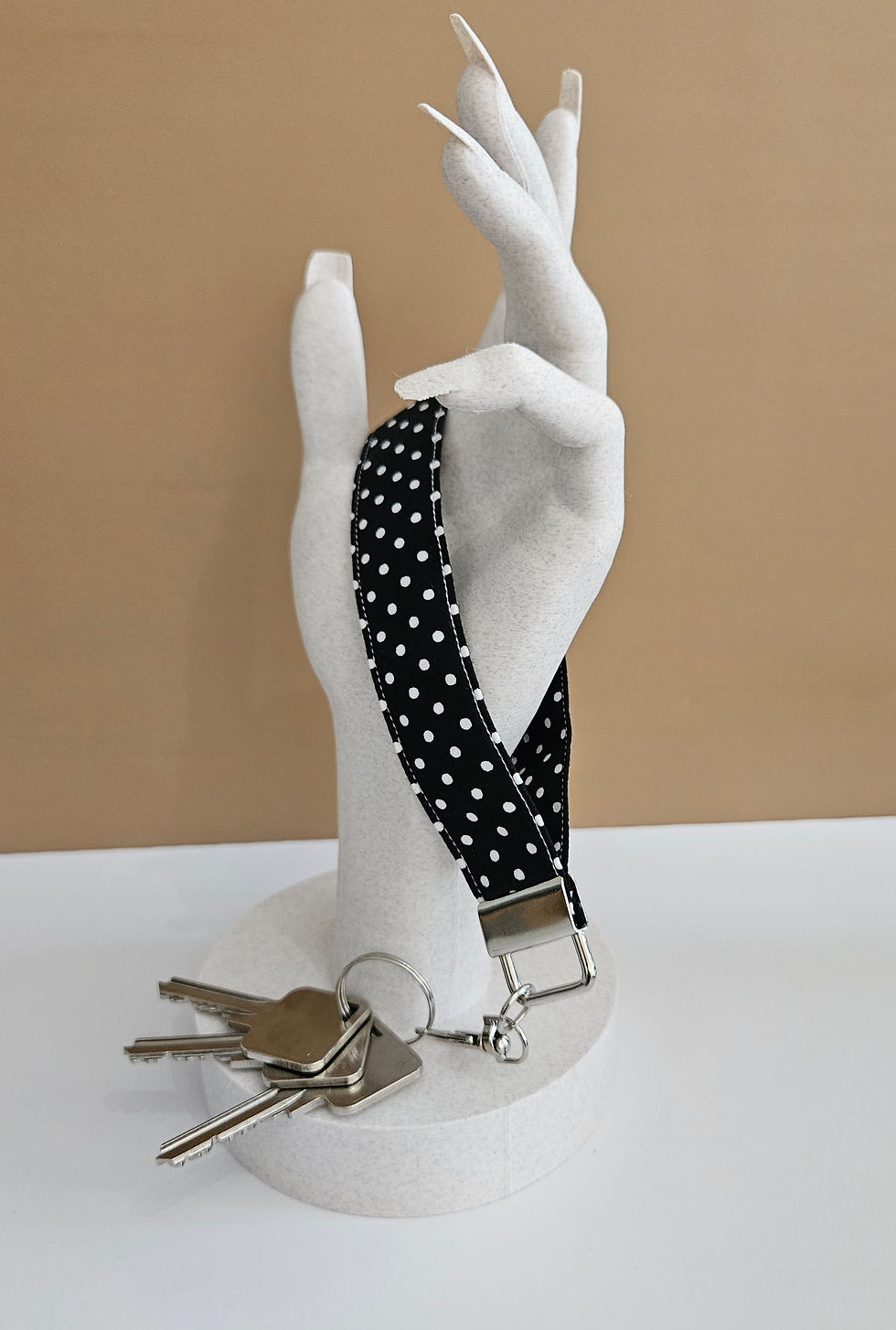 Thumbnail: black with white polka dot print fabric wristlet phone tether in mobile case displayed in a hand