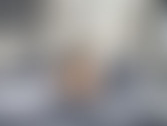 Woman in White Tank Top Lying on Gray Bed