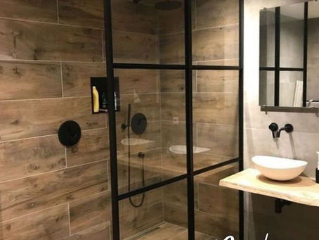 Inspiration salle de bains avec douche à l'italienne de style industriel : paroi vitrée avec profilés noirs, carrelage mural effet bois chaleureux et vasque à poser blanche sur plan en bois