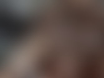 Hair extensions are being applied to brown hair with a comb and clip. The setting appears to be a salon with a neutral background.