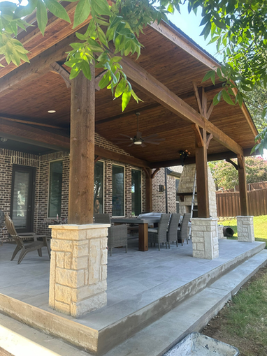 Rustic covered patio with wooden beams and stone columns, creating a warm and inviting outdoor living space.
