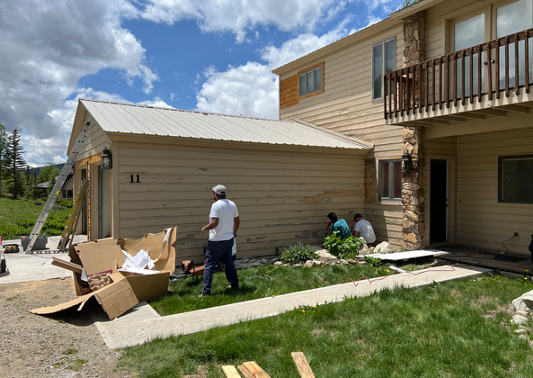 Workers clearing and prepping the area for new siding installation.