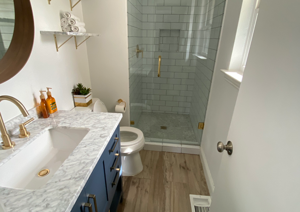 Small bathroom featuring a blue vanity, marble top, and round mirror.
