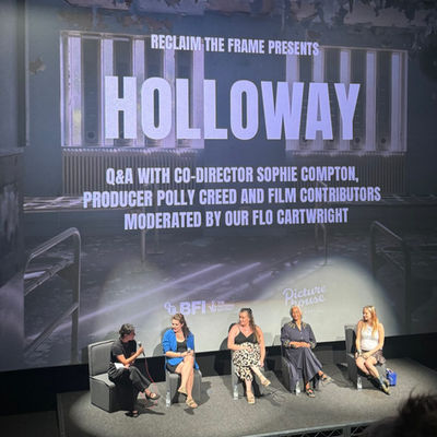 5 people sitting on a stage for a Holloway film Q&A panel beneath a large projected title screen.