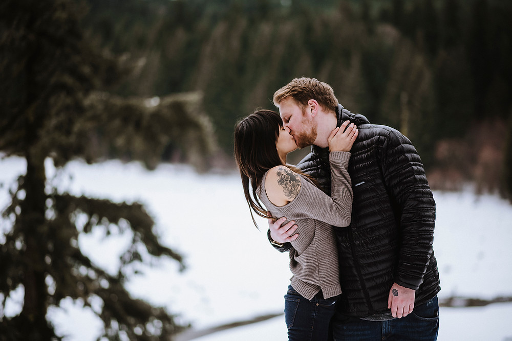 Engagement photos, couple kissing in snowy forest
