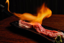 炎で炙る和牛肉寿司をドラマチックに捉えた料理写真