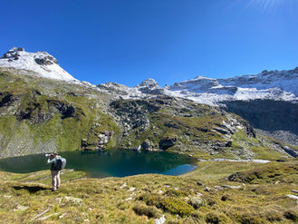 Fotograf in Bergkulisse mit See