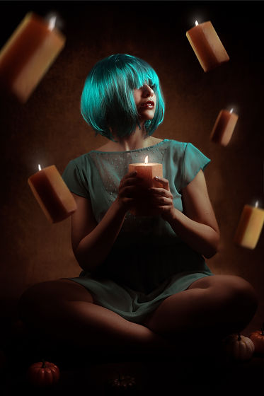 Pretty dramatic portrait of woman with blue hair surrounded by floating candles for autumn