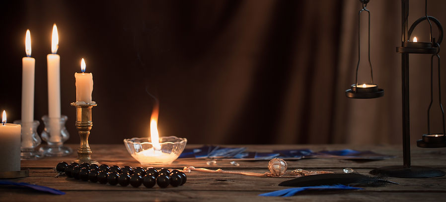fortune-telling cards and burning candles on a wooden table on dark brown background.jpg