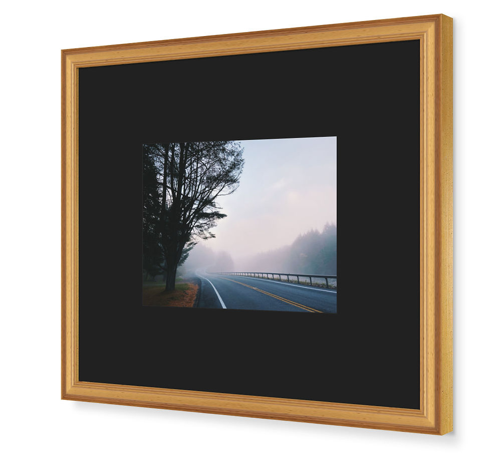 Side view of foggy landscape photograph. The atmospheric highway art is presented in a gold frame with black mat board.