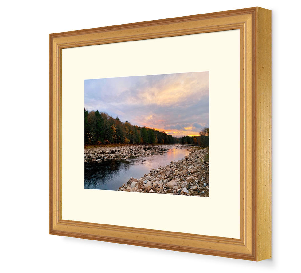 Side view of a small, gold framed photo depicting a golden pink sunset over a river.