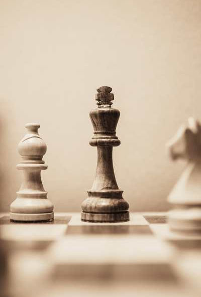 Königsfigur aus dem Schach auf dem Schachbrett. Pferd leicht verschwommen im Vordergrund.