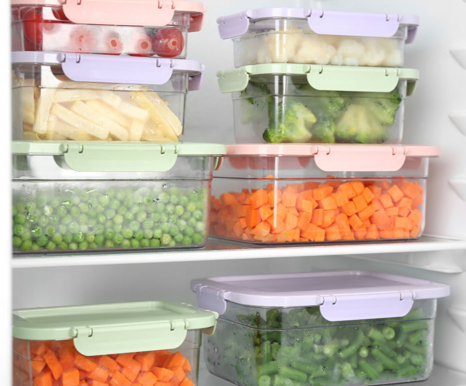 Glass containers filled with prepped veggies, stacked in a fridge.