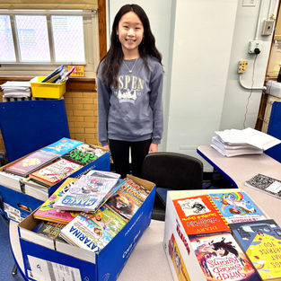 hundreds of books in boxes sitting on top of a table donated to school