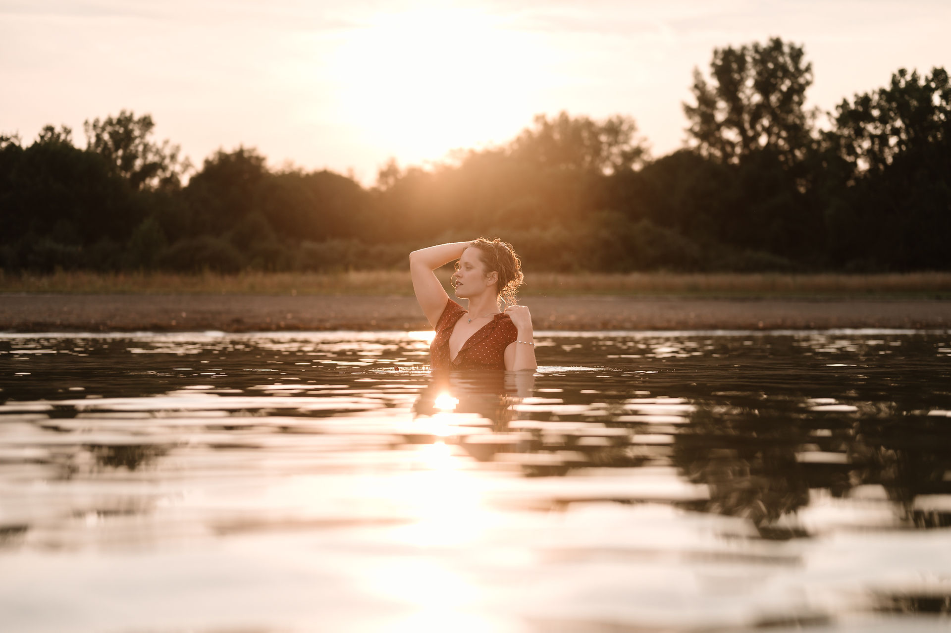 A young woman in a lake, running her hands through her hair