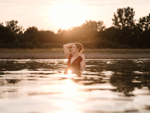 A young woman in a lake, running her hands through her hair