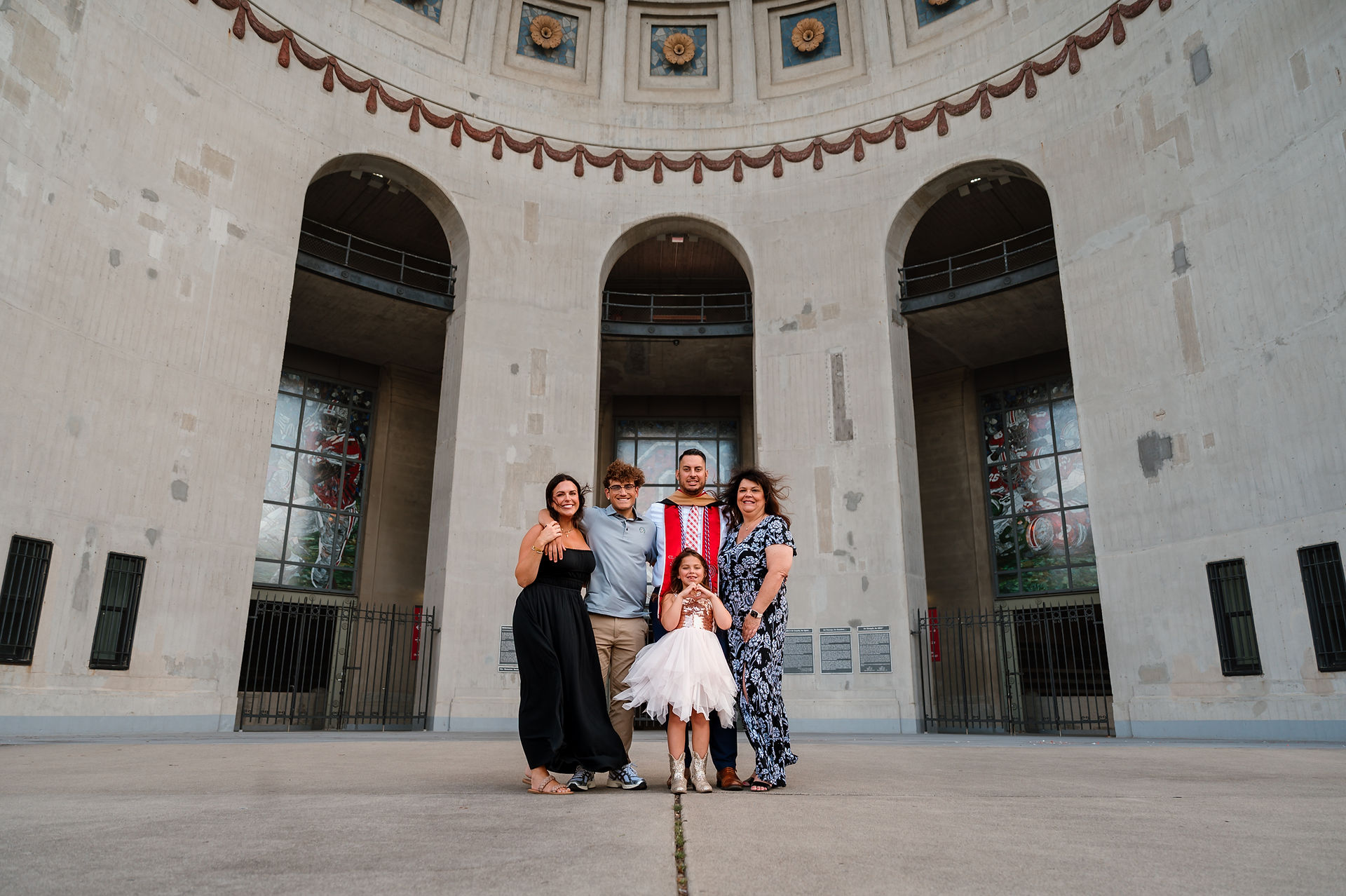 A family gathers around a college graduate for a portrait in front of OSU stadium.