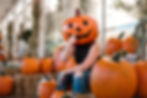 A woman wearing a pumpkin head prop for a portrait
