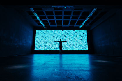 Eine Person steht vor einer größen LED Wall mit blauer Farbe