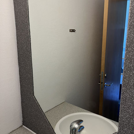 Badeværelse efter renovering med kontrasterende farver, hvor hvide gulvfliser og grå mosaikpuds skaber et iøjnefaldende udseende
