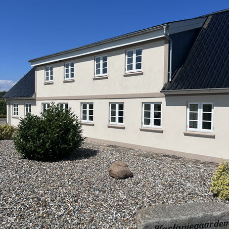 Renoveret husfacade med cremet maling og dekorativt smuk cremet mosaikpuds