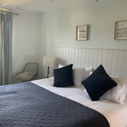 Gentle tones in double bedroom with wall and headboard in softest grey with a navy accent in soft furnishings