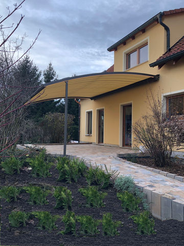 gelbe Markise gebogen an gelbem Haus auf Terrasse