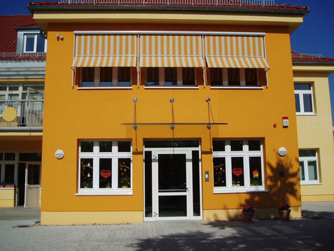 Gelbes Gebäude mit Markisen und Sonnenschutz