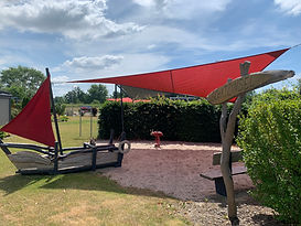 Spielplatz mit rotem Sonnensegel und Piratenspielschiff