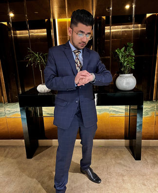 Aditya Agarwal, also known as Addy 323 in navy suit looking at Apple watch
