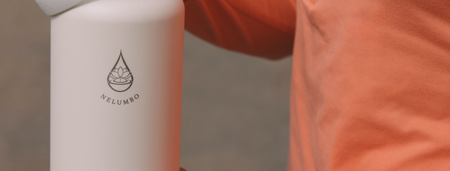 Person holding white water bottle with logo, wearing orange long sleeve shirt.