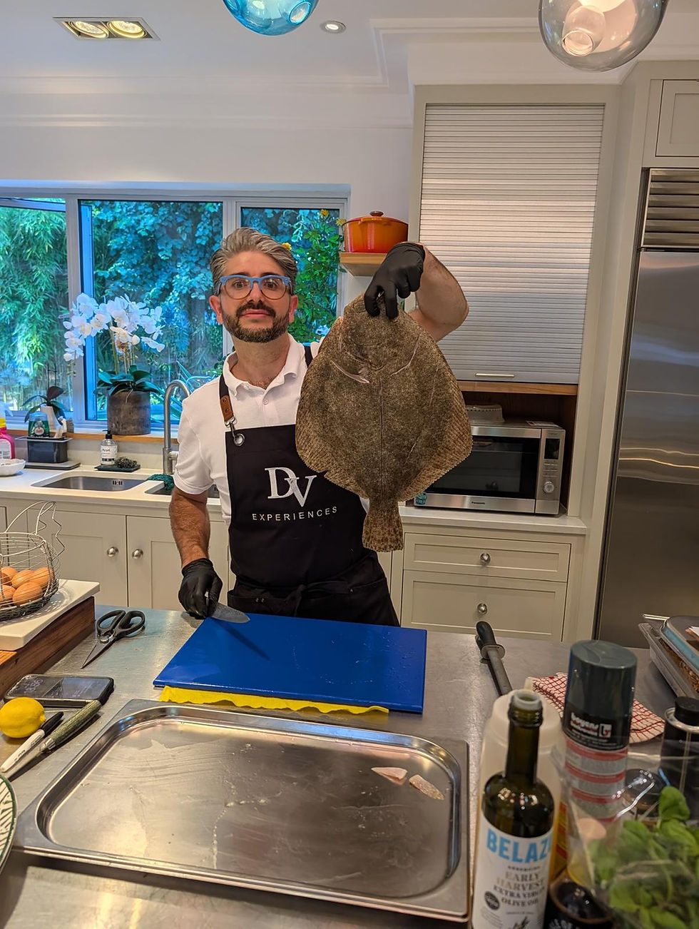Chef holding a whole turbot fish in a bright kitchen