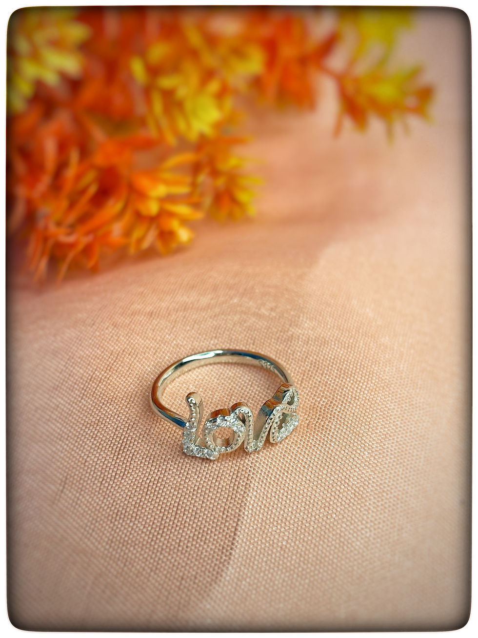 925 Sterling Silver 'Love' Ring with Sparkling Stones on Peach Fabric