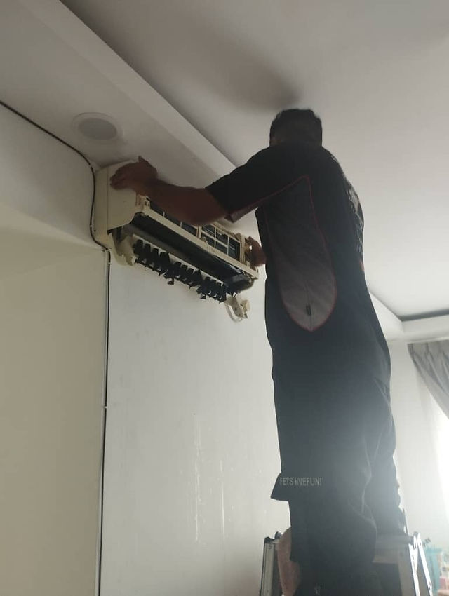 Technician replacing a faulty capacitor on an outdoor unit.