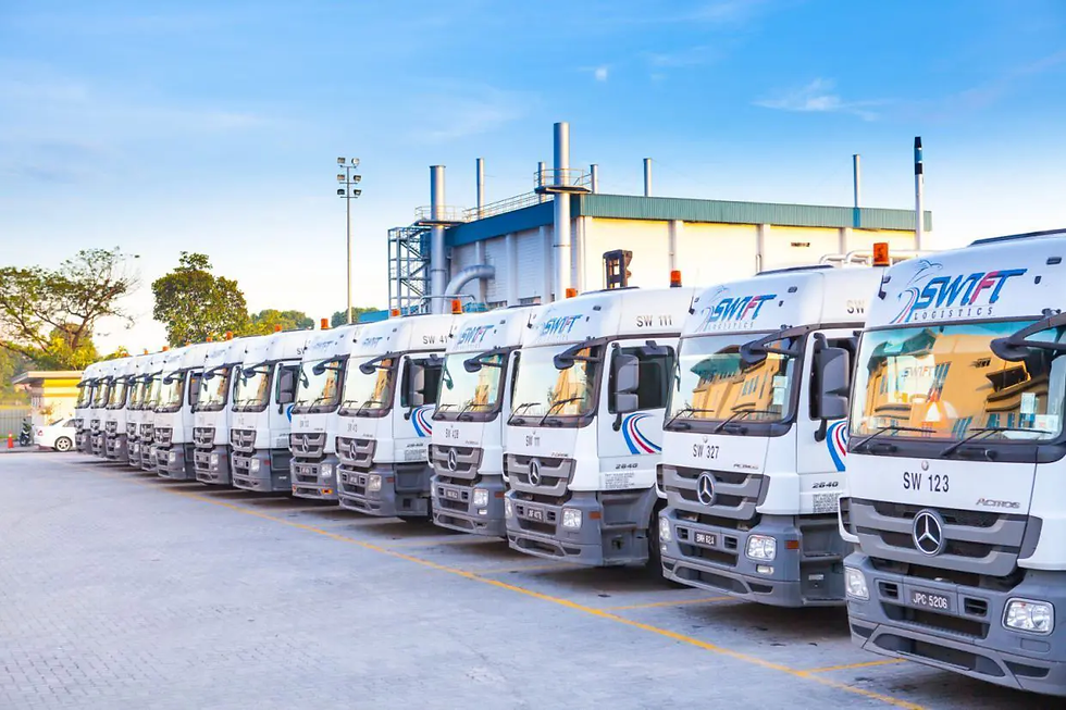 Row of white transport trucks with "Swift Logistics" logos parked beside an industrial building under a clear blue sky.
