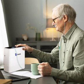 Senior man operating a compact desktop oxygen concentrator at home