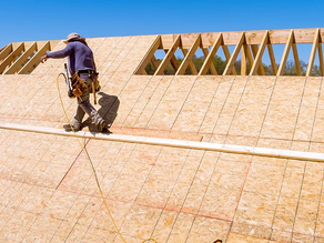 Contractor performing roof decking repair on two-storey house