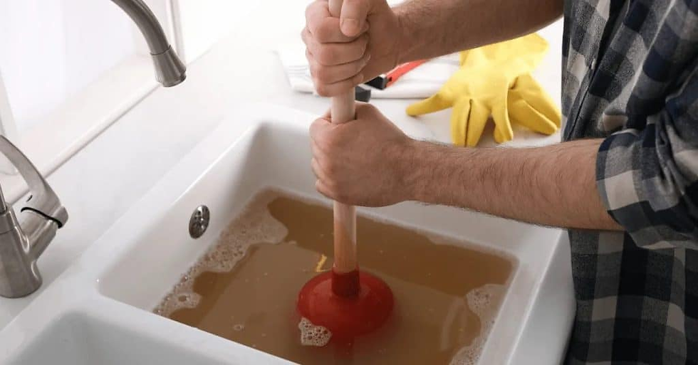 Kitchen clogged sink being repaired by expert plumber