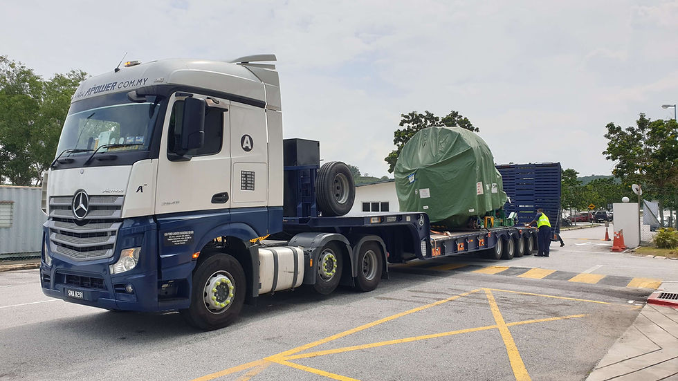 Low loader with crane handling loading work at a construction yard.
