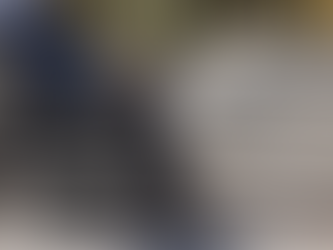 Man in a electric wheelchair gazes at the ocean during sunset. He wears a blue shirt; the sky is pink, creating a calm, reflective mood.