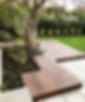 Timber deck surrounded by lush garden borders and potted flowers