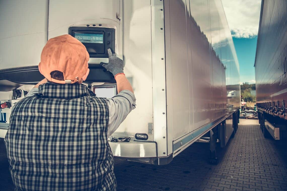 Pekerja berbaju kotak-kotak dan berkopiah memeriksa monitor suhu pada trak yang disejukkan. Hari yang cerah, langit biru, antara dua treler.